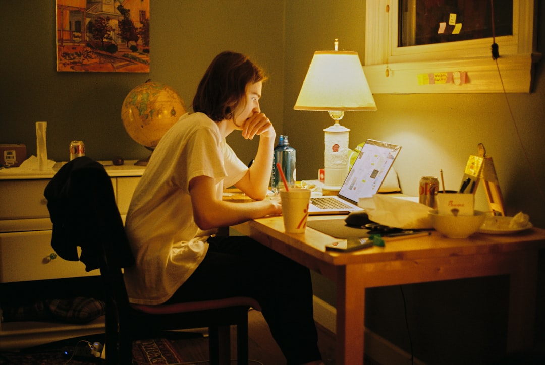 Person sitting at a warmly lit desk late at night, working on a laptop — a candid personal reflection moment. Photo by Unsplash.